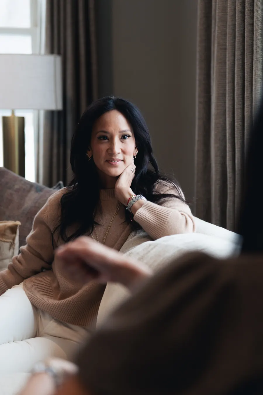 Dr. Valerie Woo on a sofa at home, resting her chin on her hand