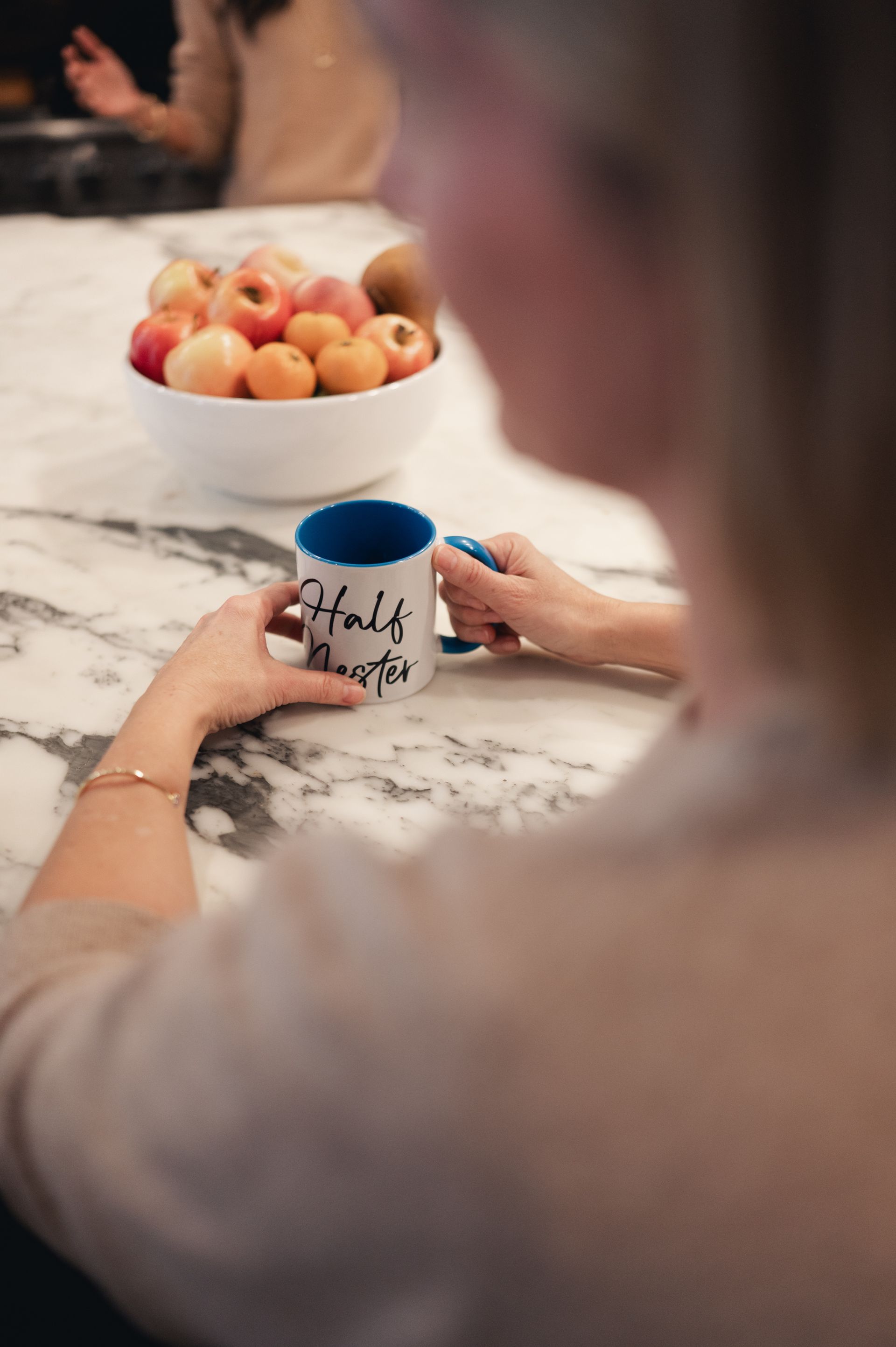 Hands holding a Half Nester mug at a desk