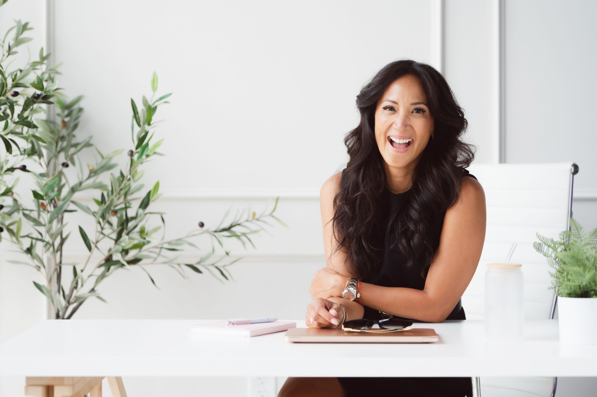 Dr. Valerie Woo laughing at a bright desk with a laptop and journal