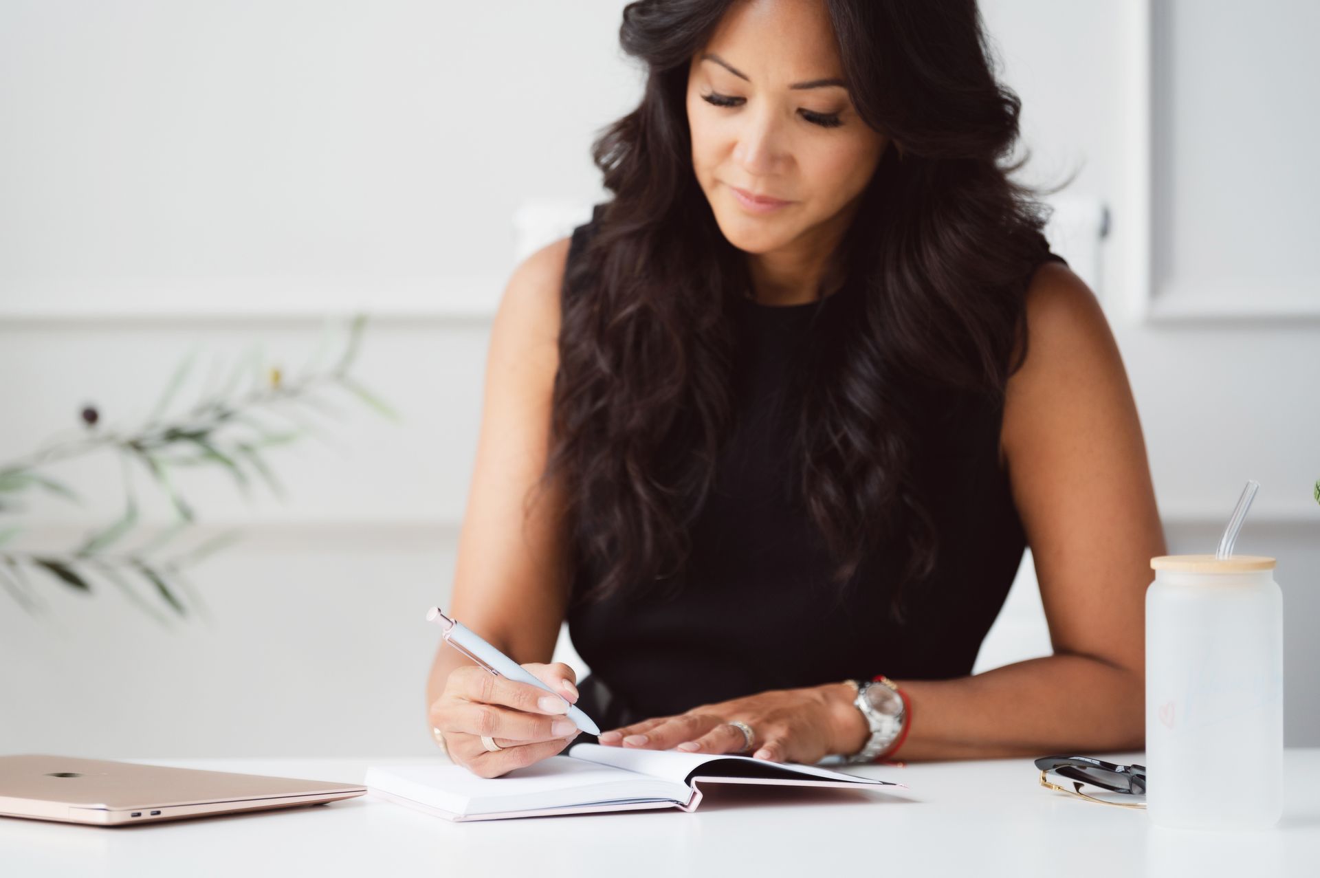 Woman sitting cross-legged near window, writing in a notebook