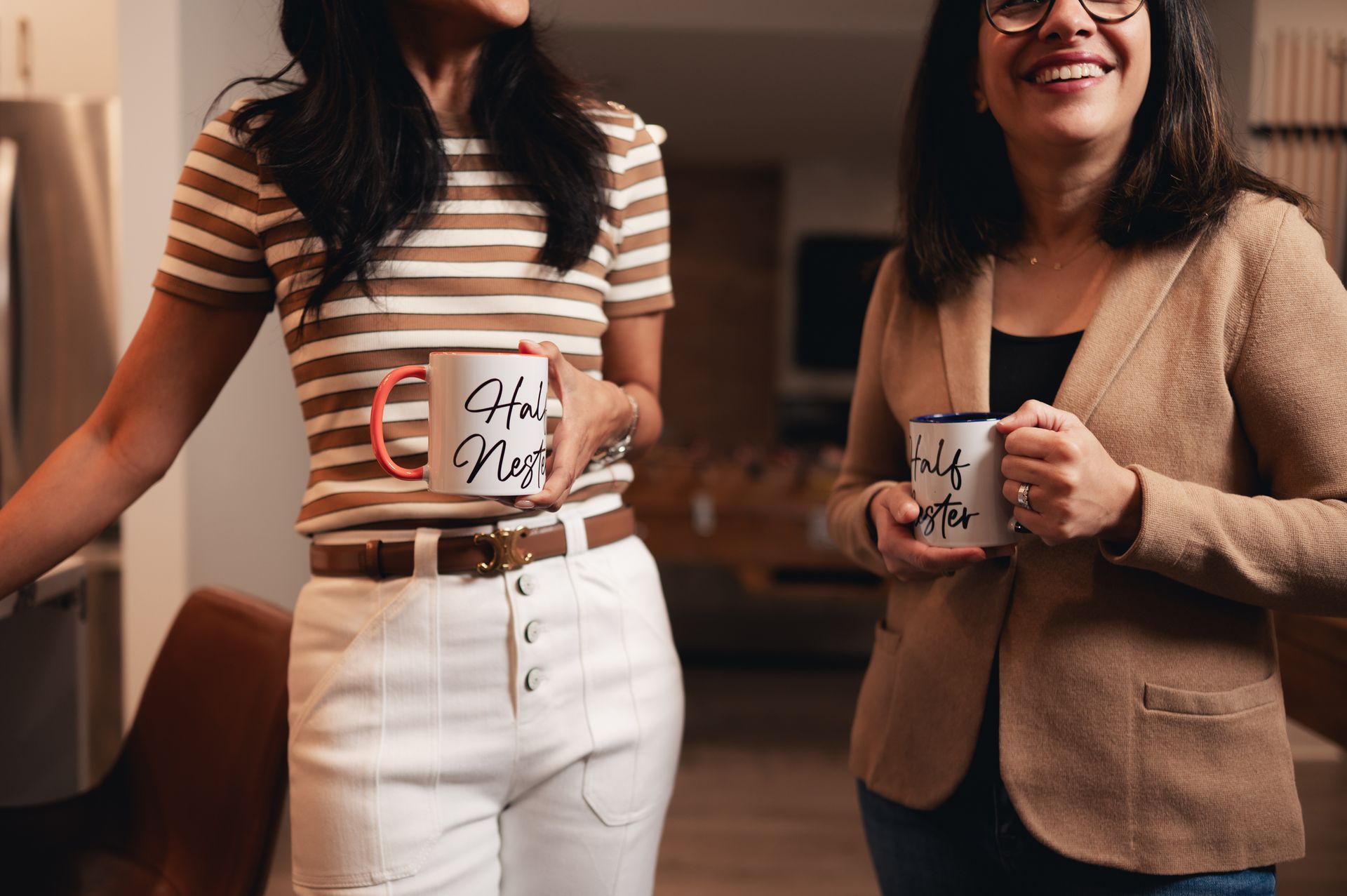 Two women laughing together while holding Half Nester coffee mugs
