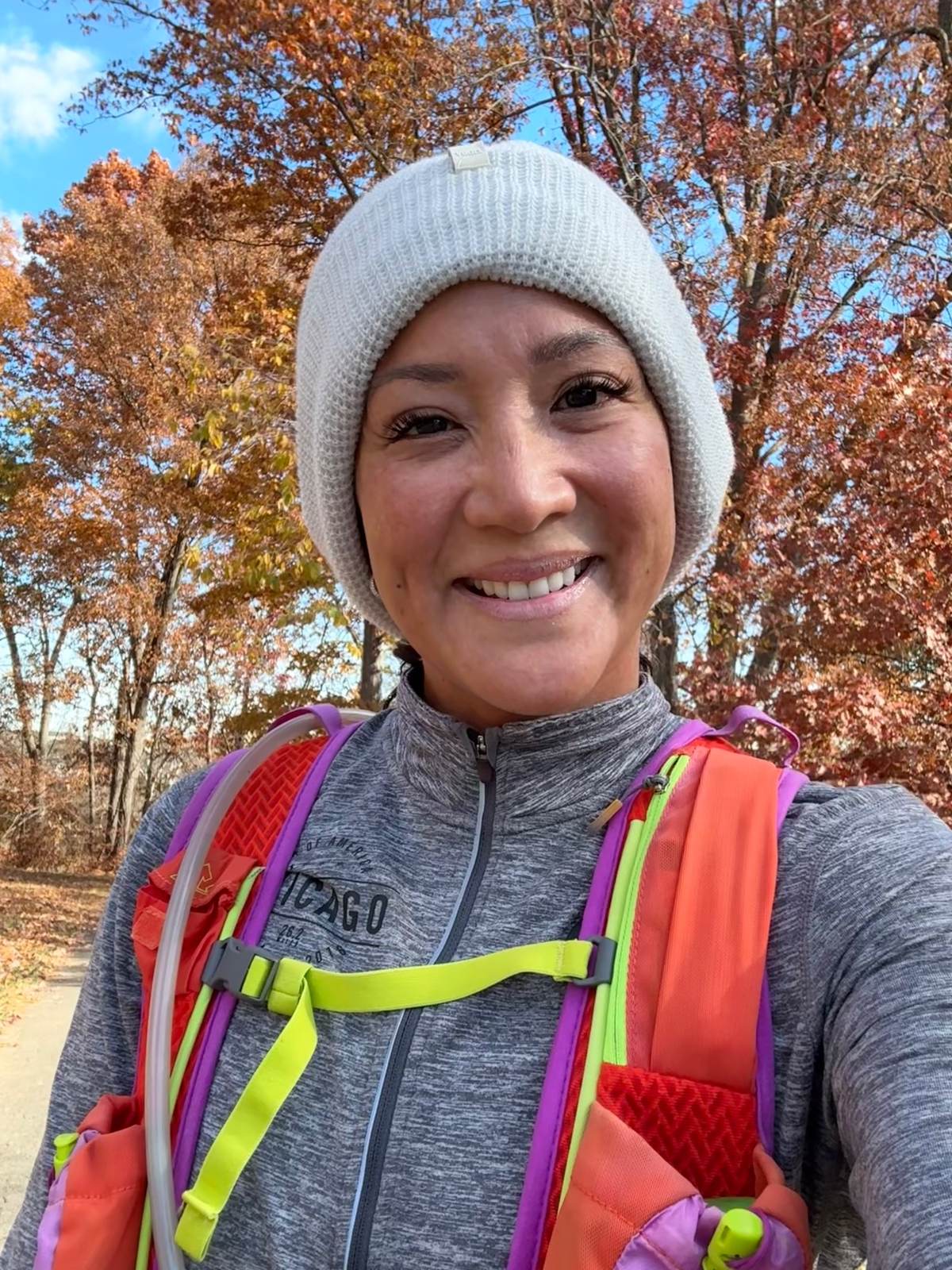 Dr. Valerie Woo outdoors among fall trees in a knit beanie and running vest